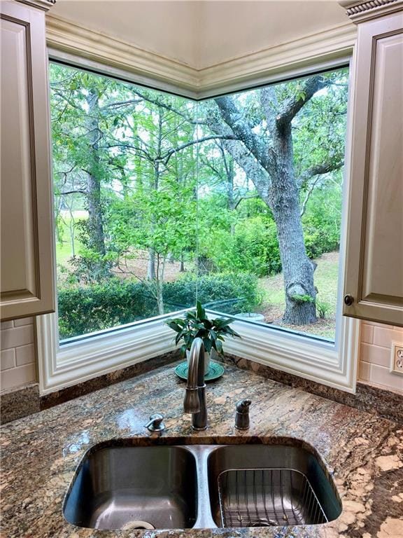 room details with tasteful backsplash, dark stone countertops, and sink