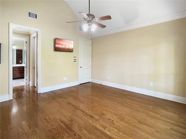 empty room featuring hardwood / wood-style flooring, vaulted ceiling, ceiling fan, and crown molding