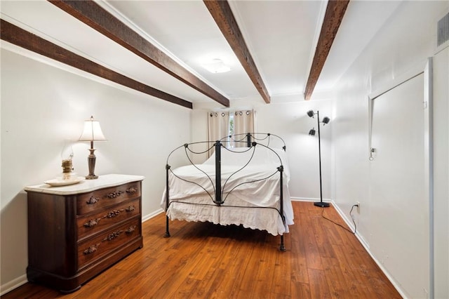 bedroom with beamed ceiling and hardwood / wood-style flooring