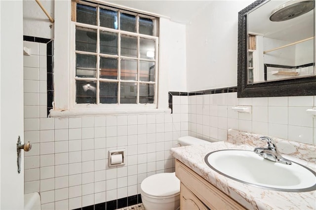 bathroom featuring vanity, toilet, and tile walls