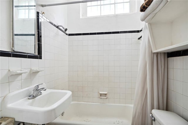 full bathroom with toilet, shower / bath combo with shower curtain, sink, and tile walls