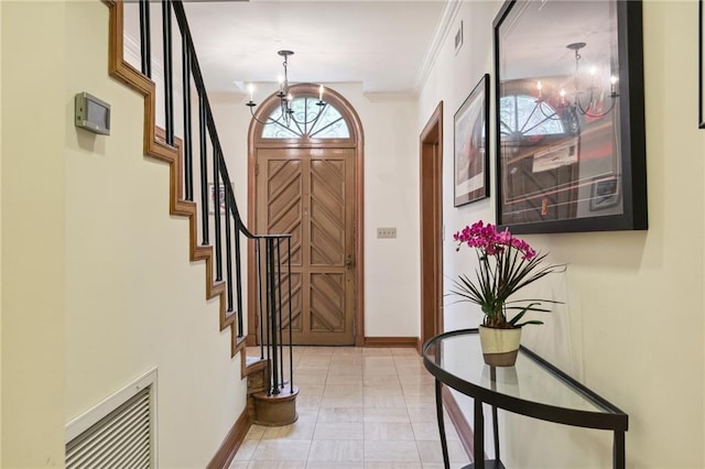 foyer entrance with ornamental molding and an inviting chandelier