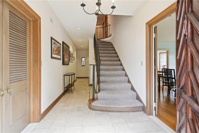 stairway featuring ornamental molding and a chandelier