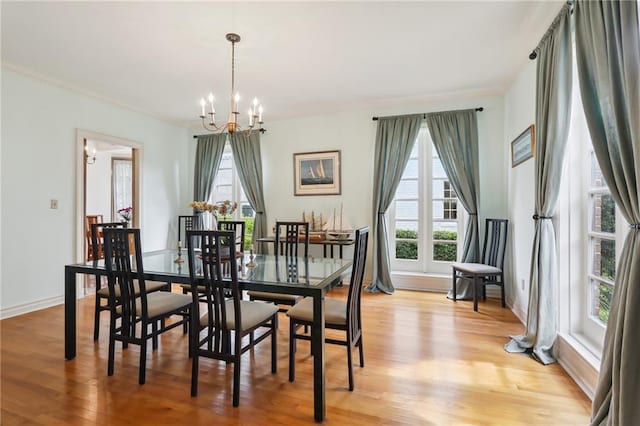 dining room featuring a healthy amount of sunlight, light hardwood / wood-style flooring, and an inviting chandelier