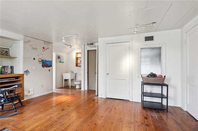 interior space with hardwood / wood-style floors and rail lighting