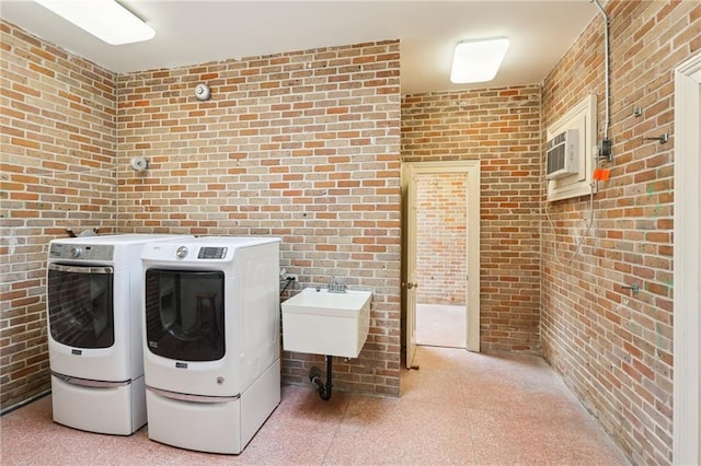 laundry area featuring washing machine and dryer and brick wall