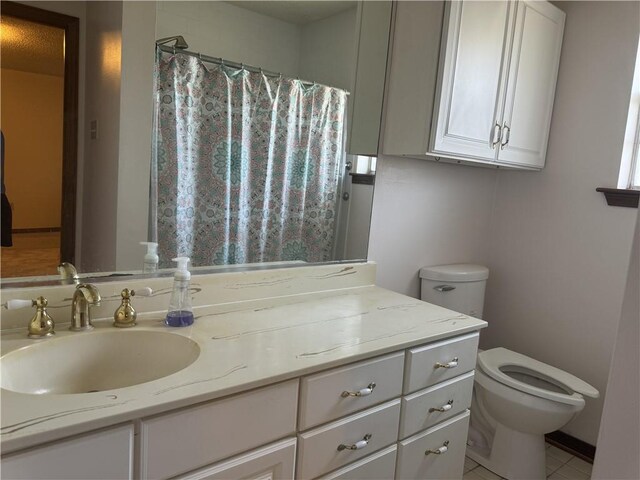 bathroom with toilet, vanity, and tile patterned flooring