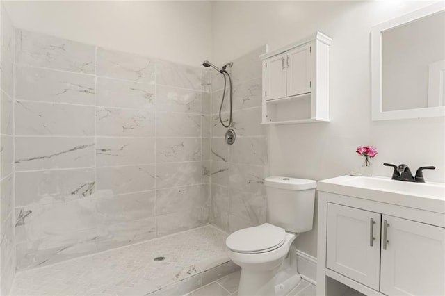 bathroom featuring tiled shower, vanity, toilet, and tile patterned flooring