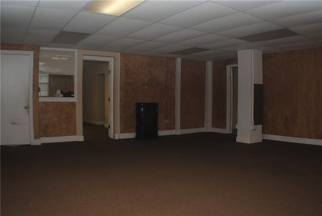 unfurnished living room with a drop ceiling and dark colored carpet