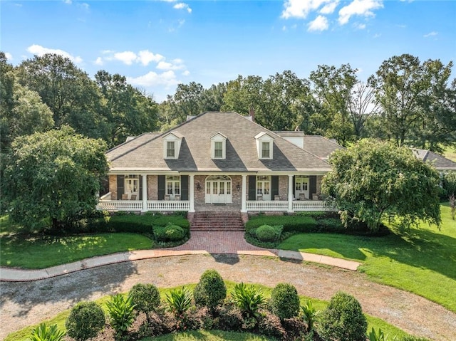 cape cod house featuring covered porch and a front yard