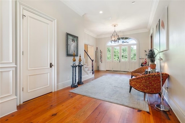 entryway featuring a notable chandelier, stairway, crown molding, and hardwood / wood-style floors