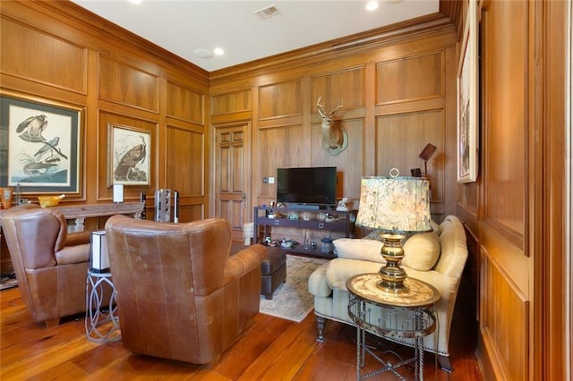 living room with a decorative wall, wood finished floors, and visible vents