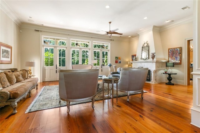 living area featuring light wood-style floors, crown molding, a healthy amount of sunlight, and visible vents