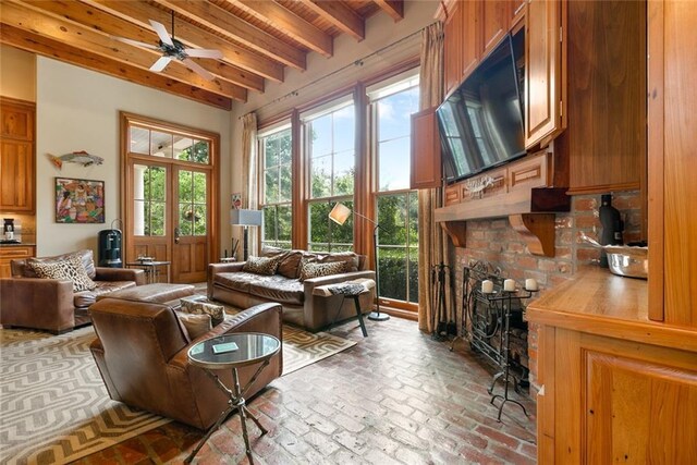 living room featuring brick floor, beamed ceiling, wood ceiling, and a ceiling fan