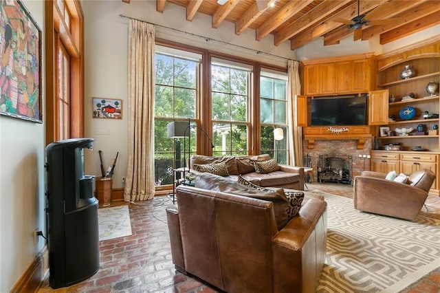 living room featuring baseboards, beamed ceiling, wood ceiling, brick floor, and a ceiling fan