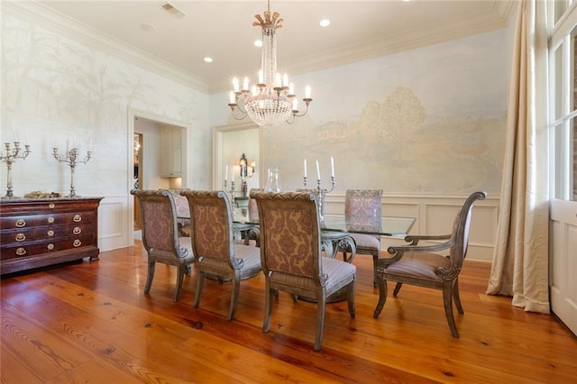 dining area featuring a decorative wall, wood finished floors, visible vents, and ornamental molding