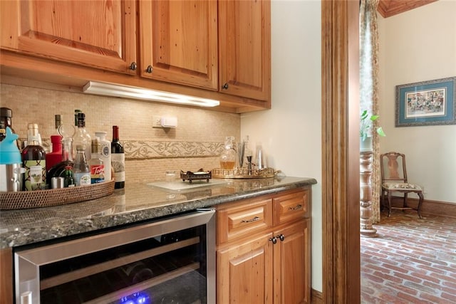 bar featuring backsplash, baseboards, wine cooler, brick floor, and a bar