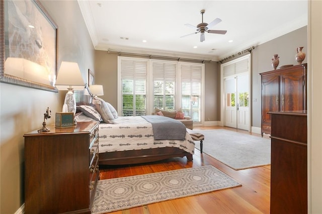 bedroom with a ceiling fan, wood finished floors, baseboards, visible vents, and crown molding