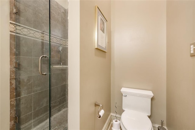 bathroom with toilet, baseboards, and a stall shower