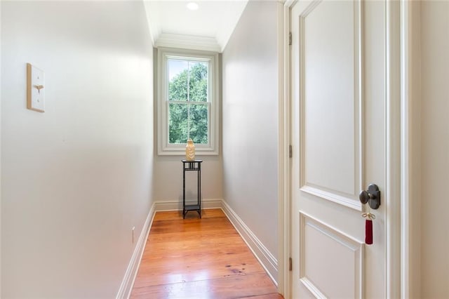 corridor featuring crown molding, baseboards, and light wood finished floors