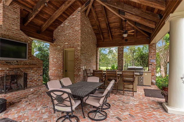 view of patio featuring area for grilling, ceiling fan, outdoor dining space, and an outdoor brick fireplace