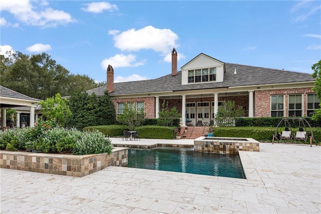 view of pool with french doors, a patio, and a pool with connected hot tub