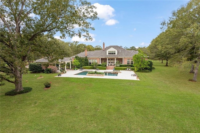 rear view of property featuring an outdoor pool, a yard, a patio, and a chimney