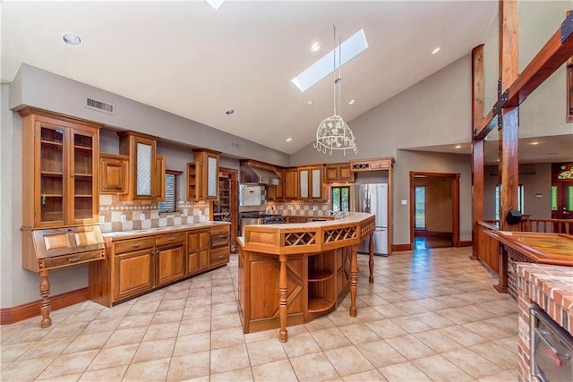 500 W Willow St, Ponchatoula, LA 70454 - kitchen with backsplash, a skylight, wall chimney exhaust hood, a center island, and stainless steel refrigerator