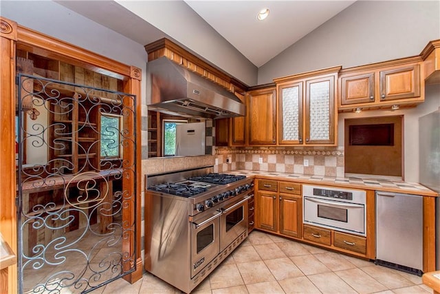 500 W Willow St, Ponchatoula, LA 70454 - kitchen featuring backsplash, wall chimney range hood, vaulted ceiling, light tile patterned flooring, and stainless steel appliances