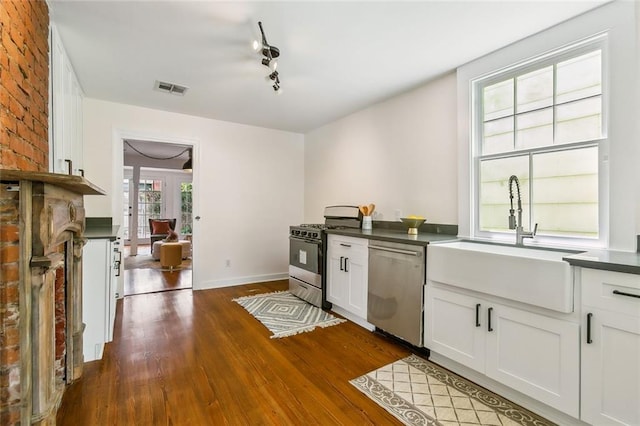 kitchen with appliances with stainless steel finishes, sink, dark hardwood / wood-style floors, and white cabinets