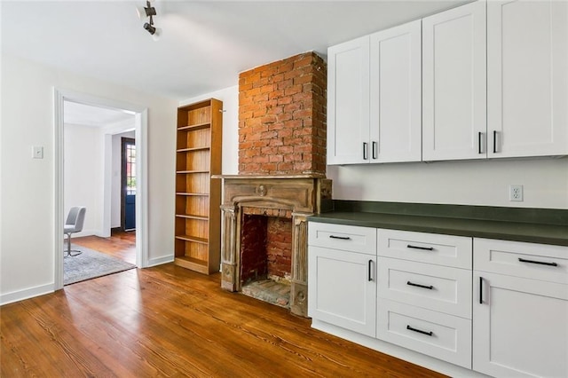 unfurnished living room featuring a brick fireplace and dark hardwood / wood-style flooring