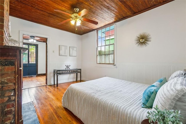 bedroom with wood ceiling, wood walls, ceiling fan, and hardwood / wood-style flooring