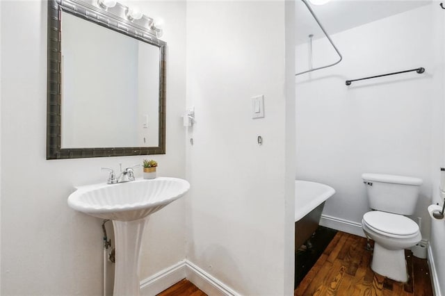 bathroom featuring hardwood / wood-style flooring, a bathing tub, sink, and toilet