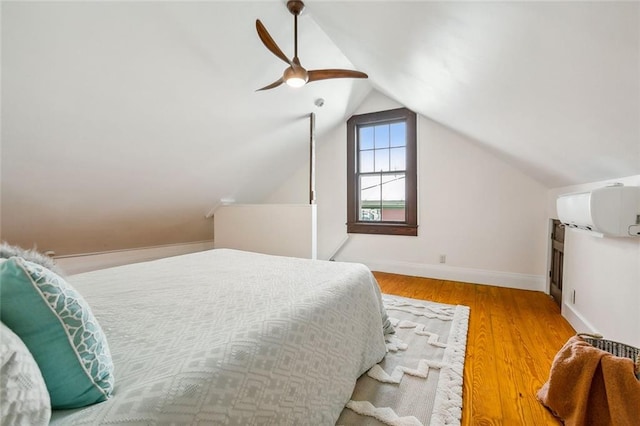 bedroom with lofted ceiling, ceiling fan, a wall unit AC, and light hardwood / wood-style flooring