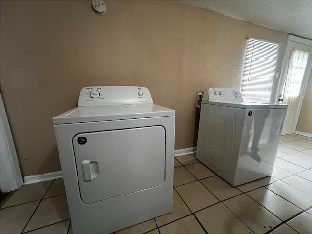 clothes washing area featuring washer and clothes dryer and light tile patterned floors