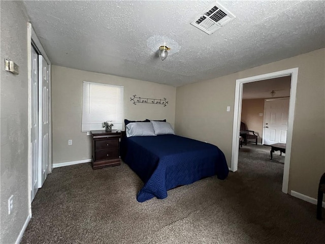 bedroom featuring dark colored carpet and a textured ceiling