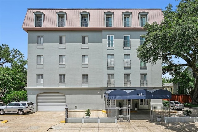 view of building exterior with concrete driveway and fence