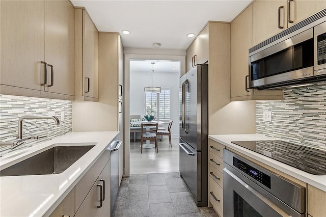 kitchen with a sink, appliances with stainless steel finishes, light brown cabinets, and light countertops