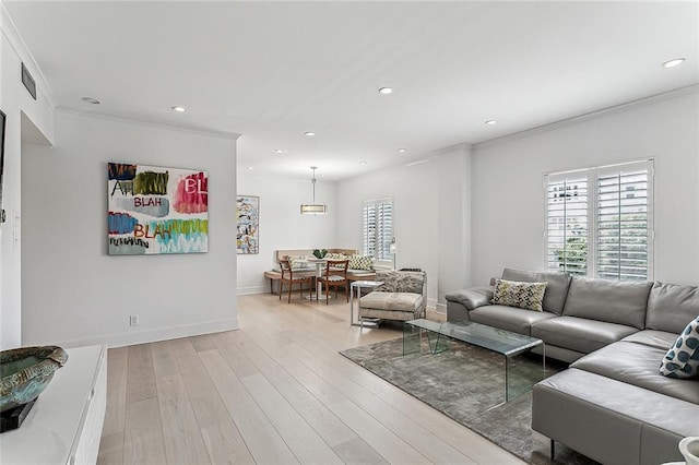 living area with a wealth of natural light, visible vents, light wood-style flooring, and crown molding