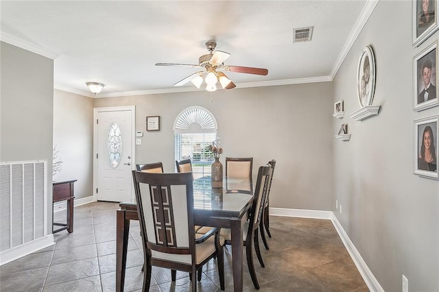 dining space with dark tile patterned flooring, ceiling fan, and ornamental molding