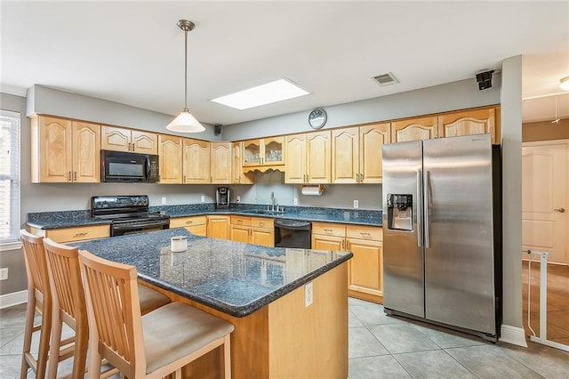 kitchen featuring a center island, sink, decorative light fixtures, a breakfast bar, and black appliances