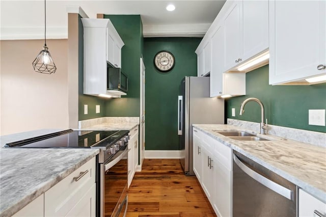 kitchen with appliances with stainless steel finishes, white cabinets, light stone countertops, sink, and hardwood / wood-style flooring