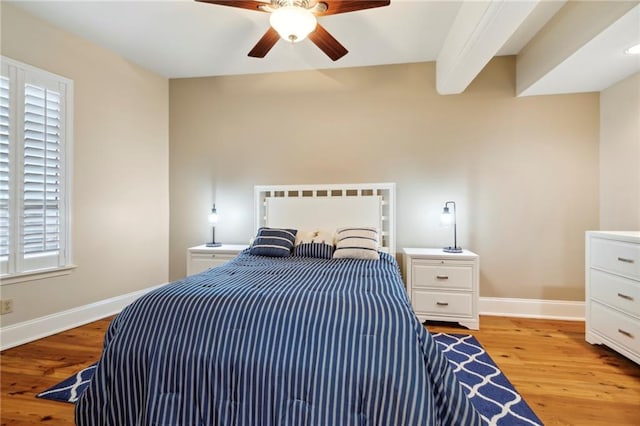 bedroom featuring ceiling fan, light hardwood / wood-style flooring, and beamed ceiling