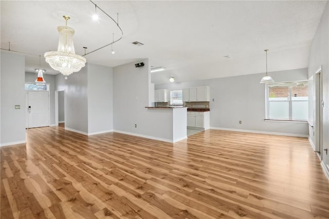 unfurnished living room featuring a notable chandelier, light hardwood / wood-style flooring, and track lighting