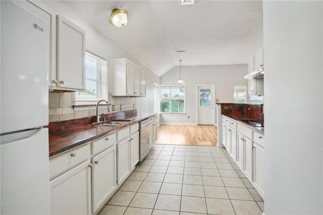 kitchen featuring white fridge, sink, tasteful backsplash, and white cabinetry