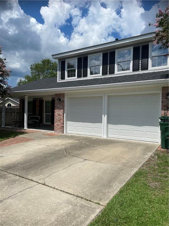 view of front facade with driveway, brick siding, and an attached garage