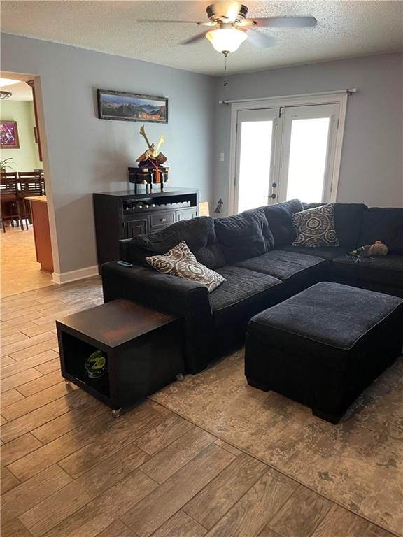 living room with ceiling fan, wood-type flooring, french doors, and a textured ceiling