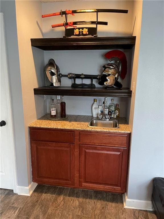 bar featuring stone counters, sink, and dark hardwood / wood-style flooring