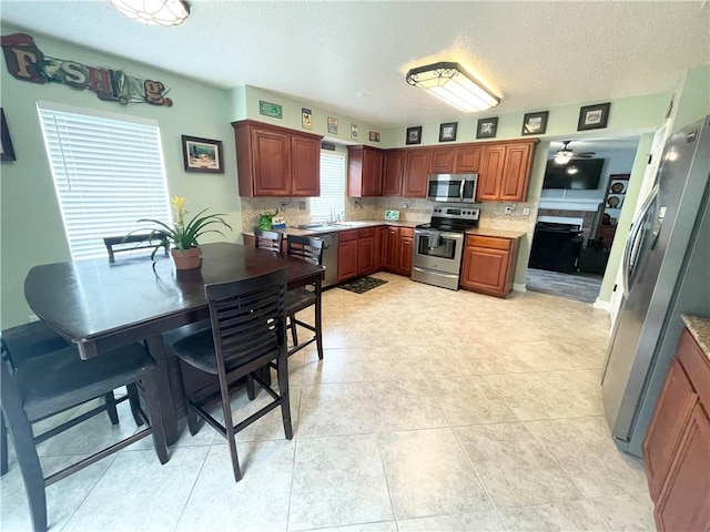 kitchen featuring ceiling fan, decorative backsplash, light tile patterned floors, and stainless steel appliances