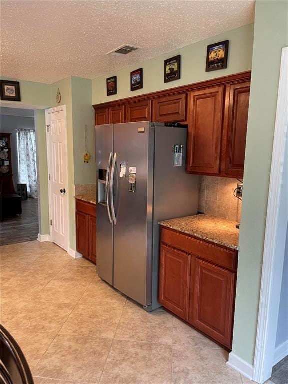 kitchen featuring backsplash, stainless steel fridge, light hardwood / wood-style flooring, and a textured ceiling